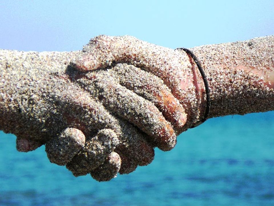 Wettbewerb: Foto : Hände der Freundschaft Mit Sand bedeckte Hände schliessen den Bund der Freundschaft.