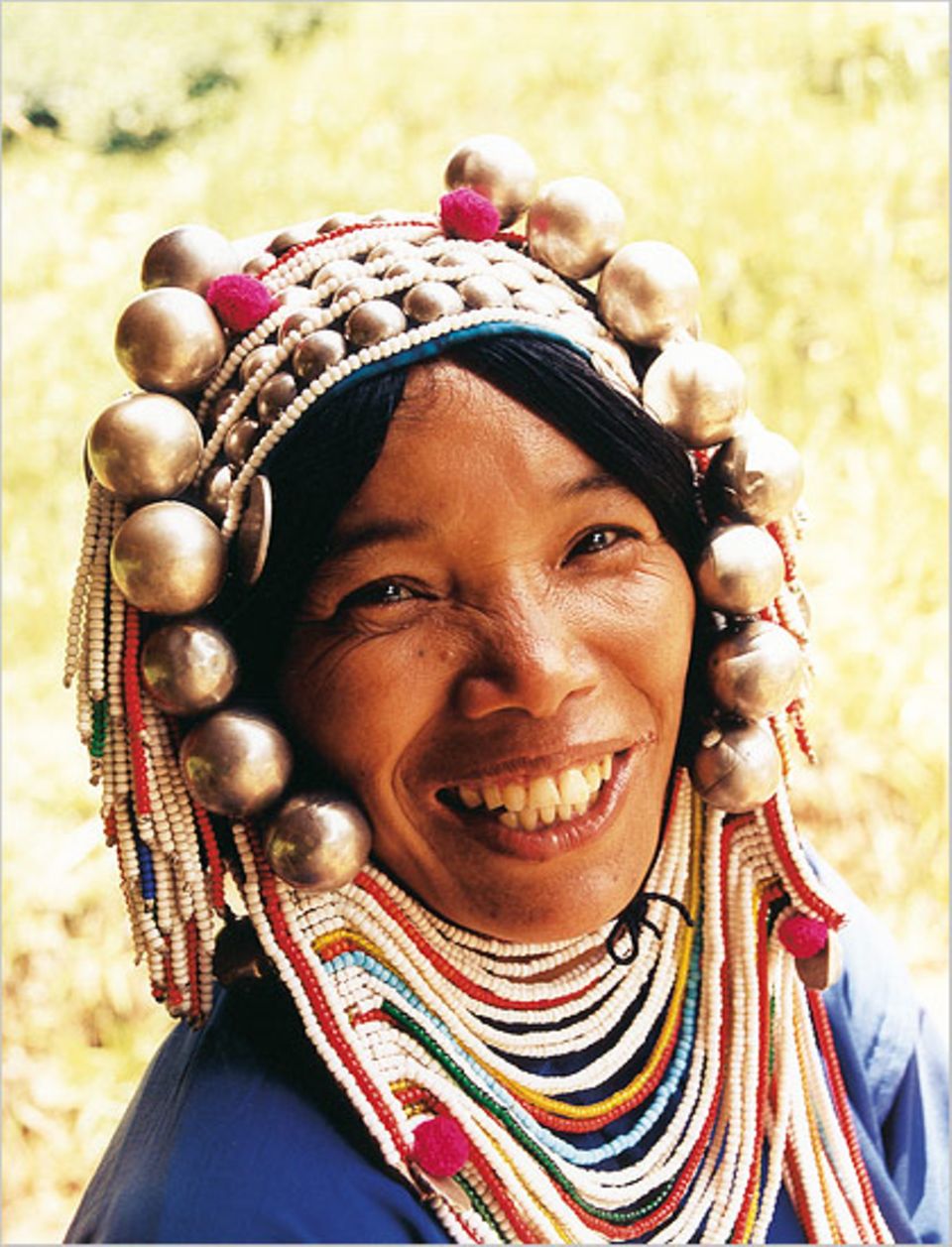 Die Frau vom Bergvolk der Akha trägt auch bei der Feldarbeit ihren traditionellen Schmuck