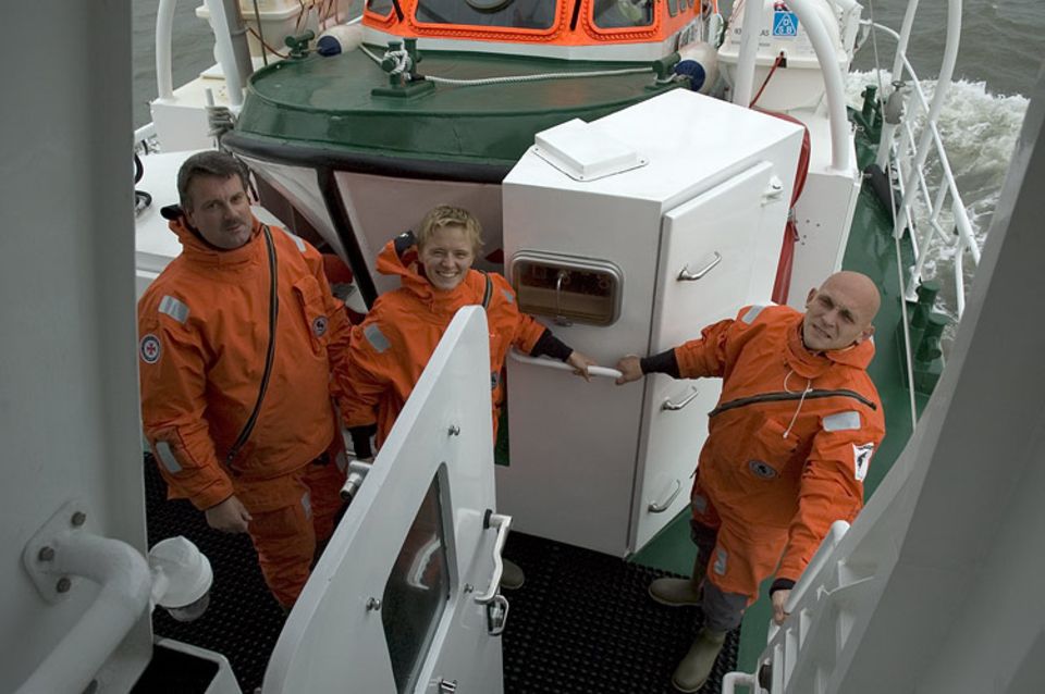Noch grinst Sina in die Kamera. Wenige Sekunden später springt sie mit Seenotretter Jochen Eicken (rechts) in die Nordsee. Sein Kollege Michael Ulrichs (links) überwacht die Übung von Bord aus