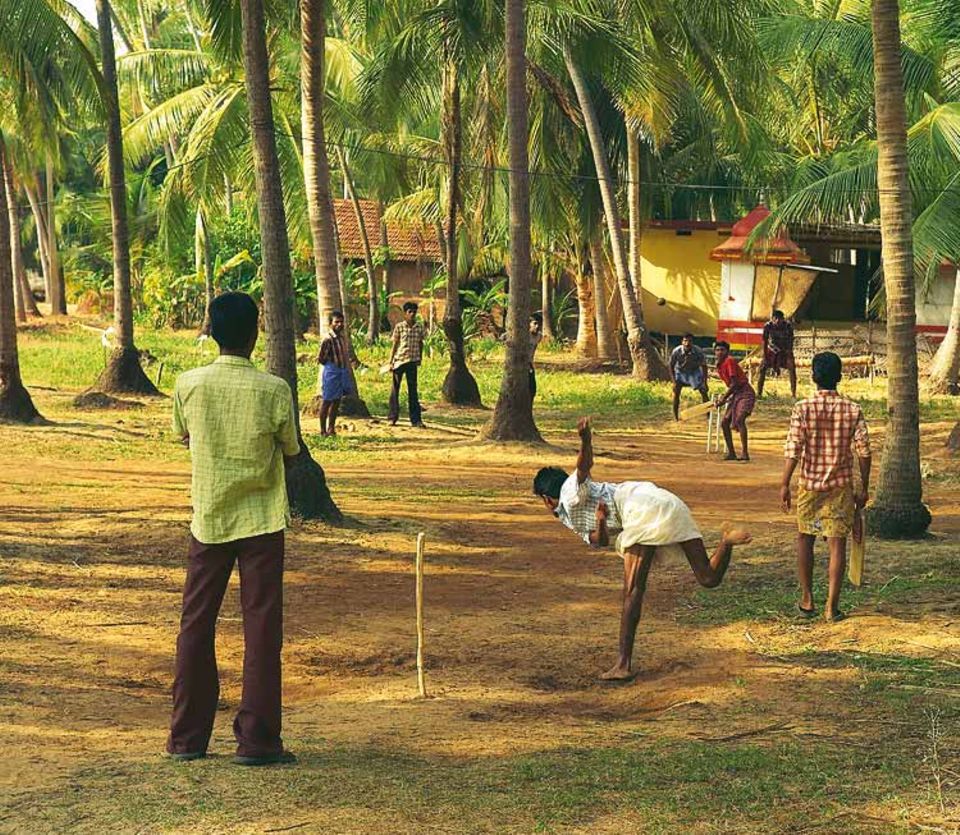 Cricket, ein Erbe der britischen Kolonialzeit, ist die beliebteste Sportart Indiens - auch bei den Jugendlichen der Insel Thekkekadu. Hinter dem Spielfeld: der gelbe und orangefarbene Tempel des Gottes Palichon Kave Cricket, ein Erbe der britischen Kolonialzeit, ist die beliebteste Sportart Indiens - auch bei den Jugendlichen der Insel Thekkekadu. Hinter dem Spielfeld: der gelbe und orangefarbene Tempel des Gottes Palichon Kave
