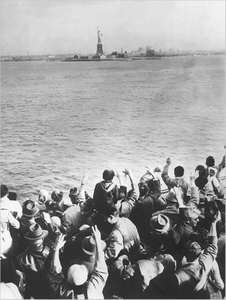 Von dem Schiff "General Langfitt" winkt im Juli 1955 eine Gruppe Flüchtlinge kurz vor ihrer Ankunft im Hafen von New York der Freiheitsstaue zu. Die 1200 Flüchtlinge wurden im Rahmen eines Flüchtlingsprogramms von den USA aufgenommen