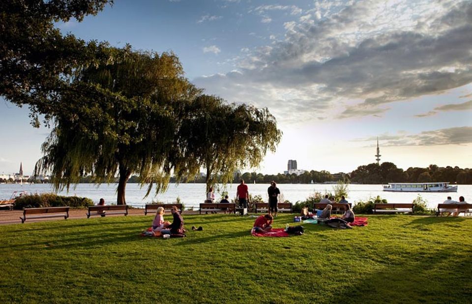 Umwelthauptstadt: Eine Wiese an der Außenalster lädt zum Picknick ein. Im Hintergrund, auf der anderen Seite der Alster ist Hamburgs Innenstadt zu erkennen Umwelthauptstadt: Eine Wiese an der Außenalster lädt zum Picknick ein. Im Hintergrund, auf der anderen Seite der Alster ist Hamburgs Innenstadt zu erkennen