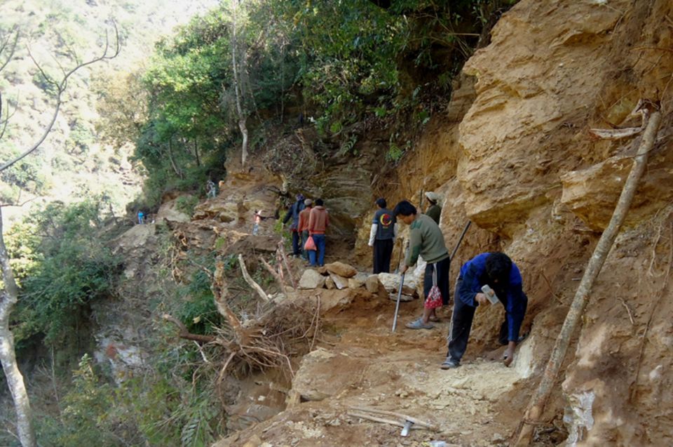 Nur mit Spitzhacke oder Hammer und Meißel, schaffen die freiwilligen Helfer Platz für den künftigen Kanal der Wasserleitung längs eines felsigen Steilhangs.