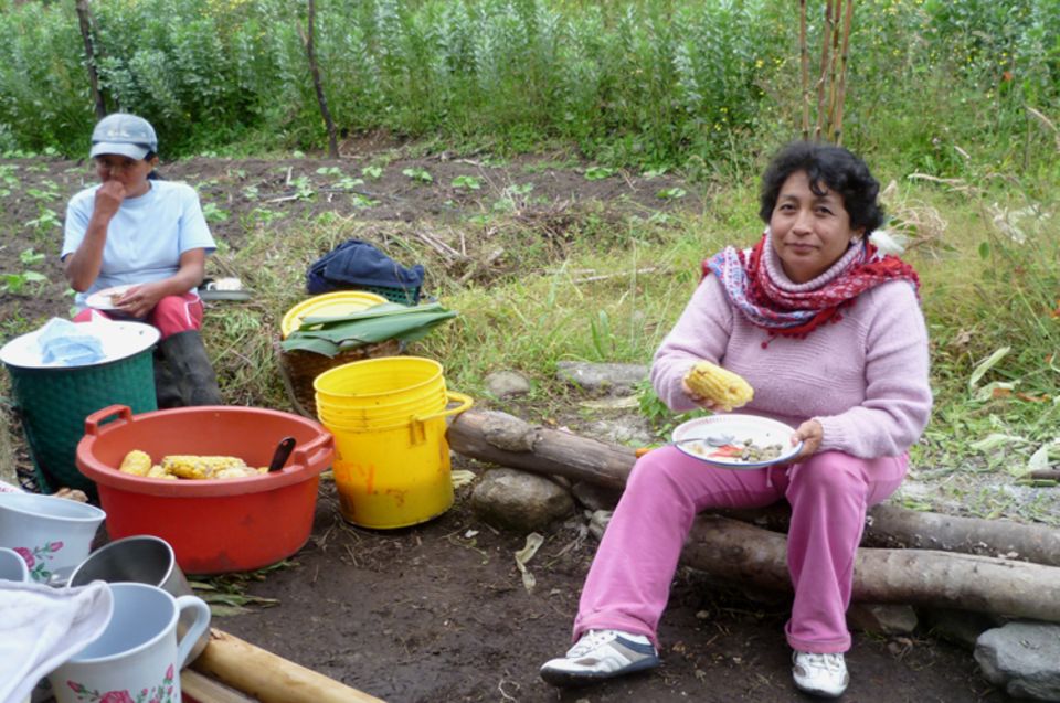 Silvia Quilumbango, Präsidentin von DECOIN, genießt einen Maiskolben mit feuriger Salsa Silvia Quilumbango, Präsidentin von DECOIN, genießt einen Maiskolben mit feuriger Salsa
