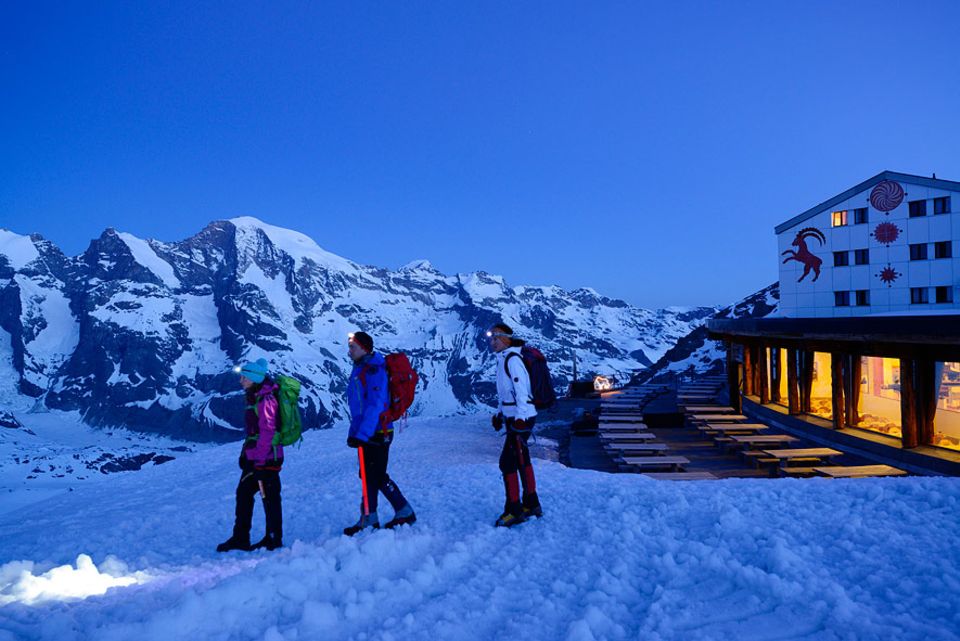 Almhütten: Drei Bergsteiger starten von beleuchtetem Gasthaus Diavolezza zum Piz Palü in Graubünden