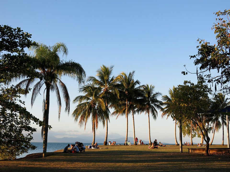 Australiens Ostküste: Backpacker und Einheimische erwarten im Anzac Park von Port Douglas den Sonnenuntergang mit Blick über das Korallenmeer