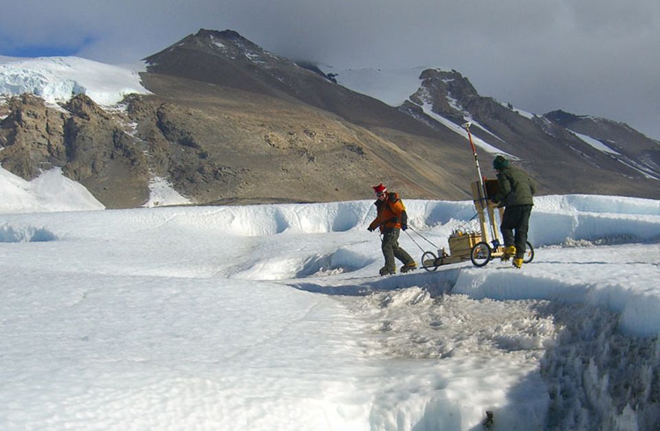 Mit einem Radargerät, das auf eine selbstgebaute Karre montiert ist, ermitteln zwei Glaziologen die Größe eines Mineralsees, der unter dem Taylor-Gletscher begraben liegt. An Orten wie diesem, so glauben sie, könnten die ersten Organismen der Erde entstanden sein.
