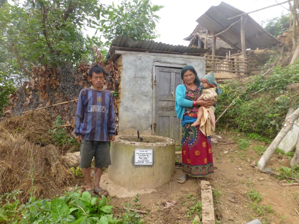 Biogasanlagenbesitzer neben dem Sammelbehälter, den sie mit Viehdung und Wasser befüllen, um Kochgas zu erzeugen