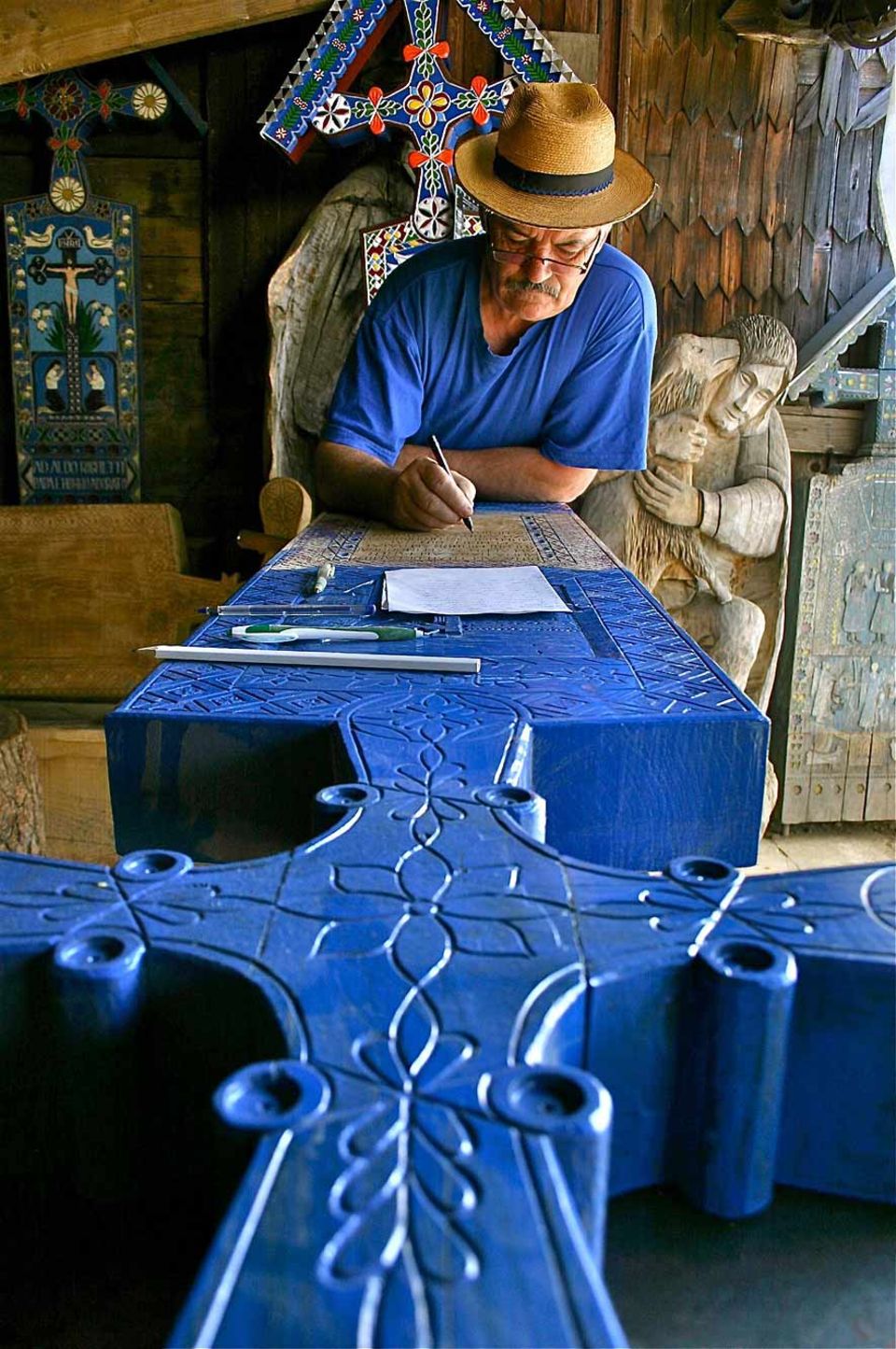 Dumitru Pop fertigt die kunstvollen Kreuze für den Friedhof von Sâpânta. Grundlage für seine ins Holz gemeißelten Texte und Bilder ist das typische, leuchtende „Blau von Sâpânta“ Dumitru Pop fertigt die kunstvollen Kreuze für den Friedhof von Sâpânta. Grundlage für seine ins Holz gemeißelten Texte und Bilder ist das typische, leuchtende „Blau von Sâpânta“
