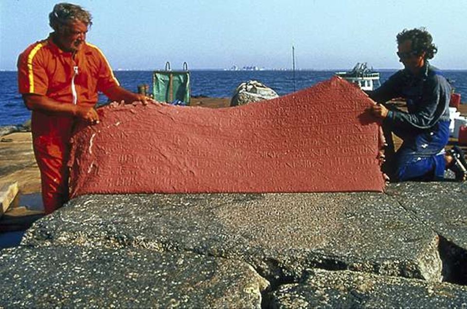 Nach dem Trocknen wird rotes Silikon von einer gefetteten Stele abgezogen - mit einem Relief der Inschriften auf dem Granit