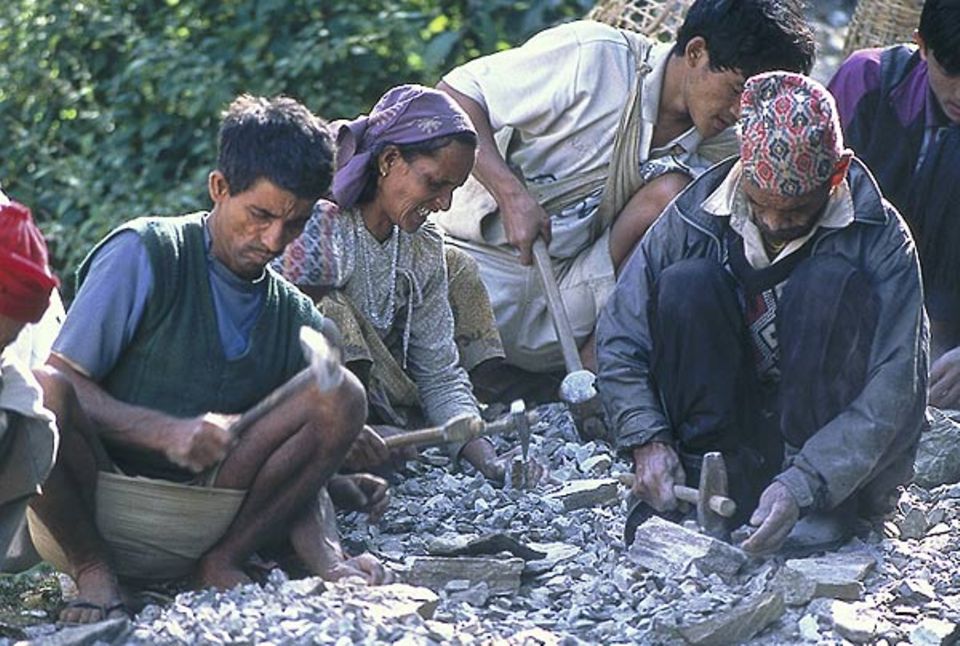 Felsbrocken zersplittern unter Hammerschlägen zu Schotter - jede Familie steckt 40 Arbeitstage in das Projekt. Felsbrocken zersplittern unter Hammerschlägen zu Schotter - jede Familie steckt 40 Arbeitstage in das Projekt.