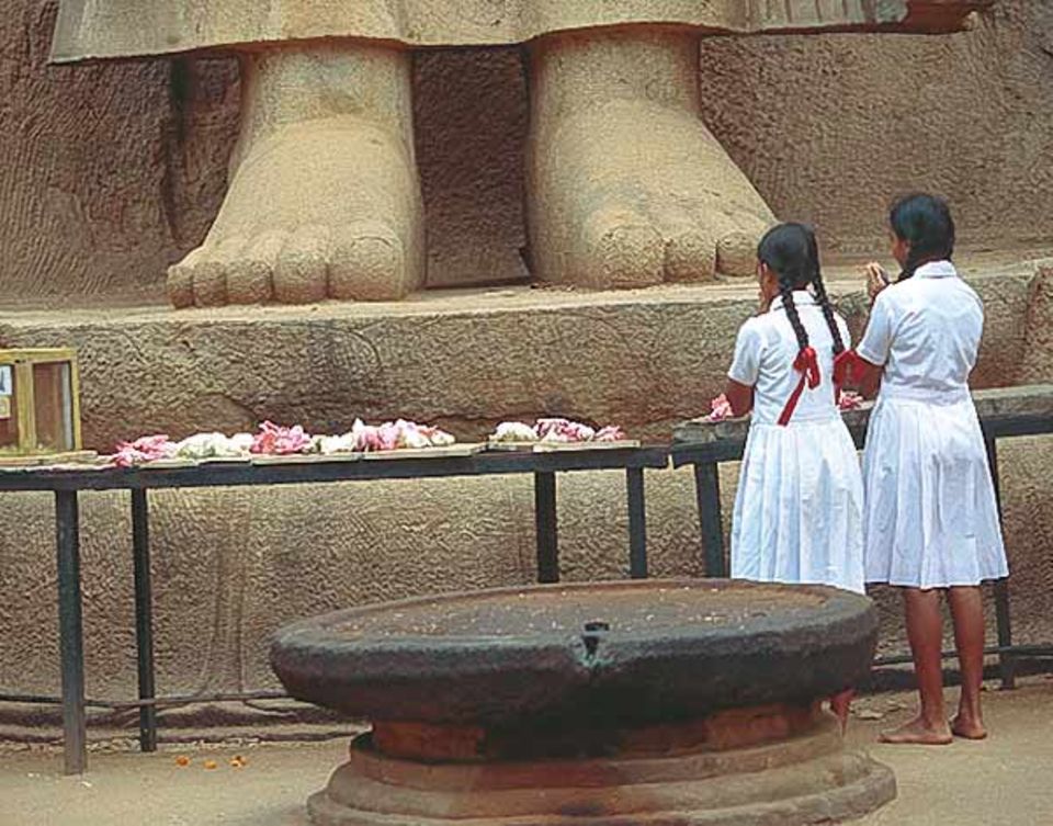 Schulmädchen beten zu Füßen der über 13 Meter hohen Buddhastatue von Aukana