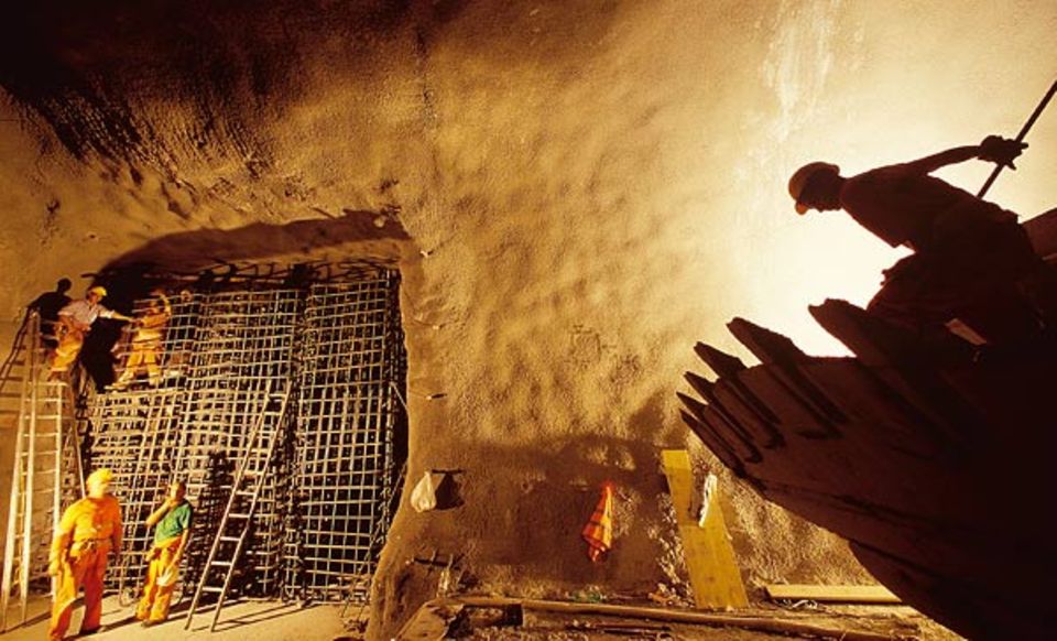 Um die Seitenwände des Tunnels zu befestigen, ziehen Arbeiter Armierungsgitter ein Um die Seitenwände des Tunnels zu befestigen, ziehen Arbeiter Armierungsgitter ein