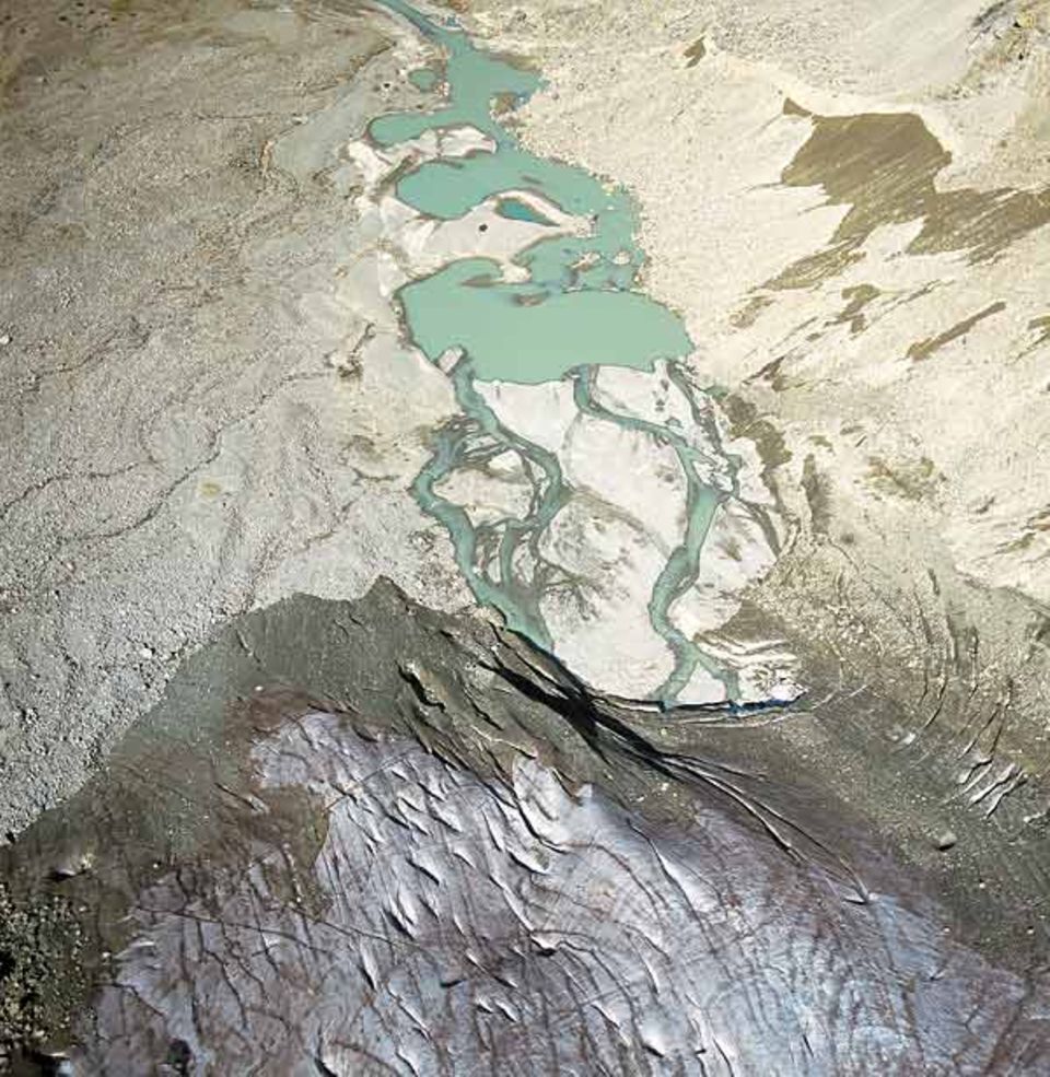 Das Gletschertor des Morteratsch-Gletschers entlässt milchiges Schmelzwasser in den Moränenschutt