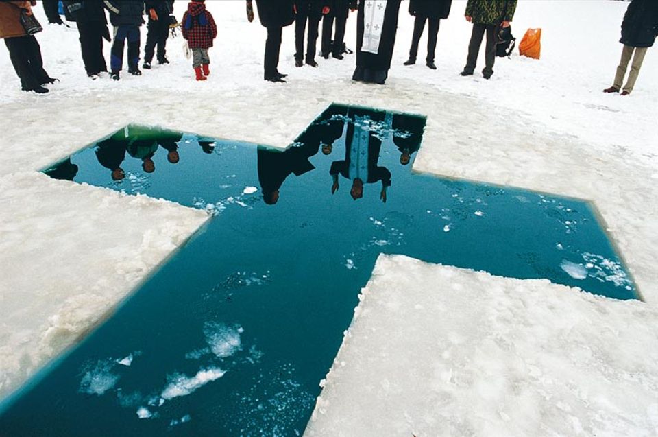 Erwachsenentaufe auf Transnistrisch: Erst spricht der Priester den Segen. Dann springen die Gläubigen in das kreuzförmige Eisloch und lassen sich weihen. Ein Schluck Wodka bringt die Lebensgeister zurück