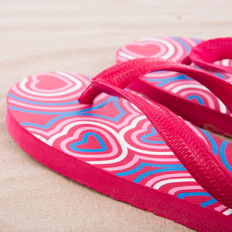 Pinke Flipflops im Sand