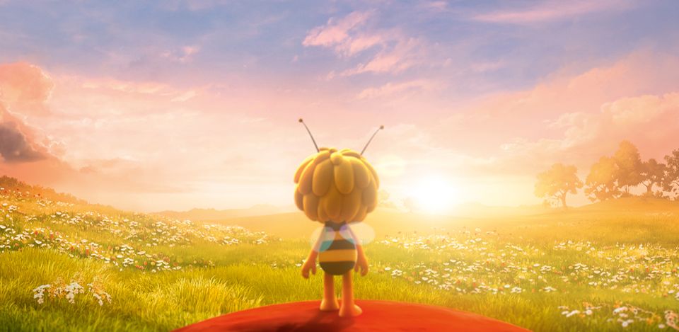 Biene Maja steht auf einer roten Blüte und schaut in den Sonnenuntergang