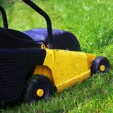 Gelber Rasenmäher auf einer grünen Wiese
