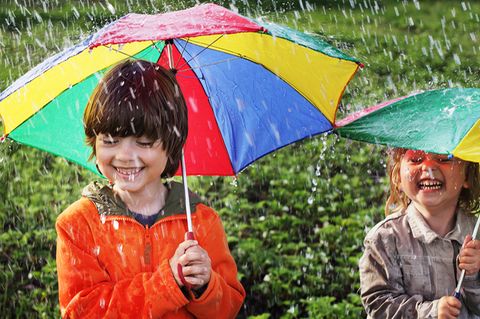 Zwei Kinder unter Regenschirmen