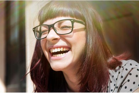 Eine Frau mit Brille lacht herzhaft