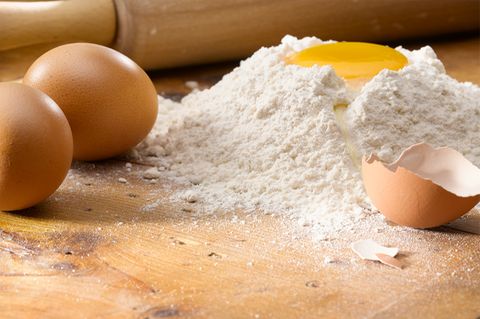 Eier, Mehl und ein Nudelholz auf einem Tisch
