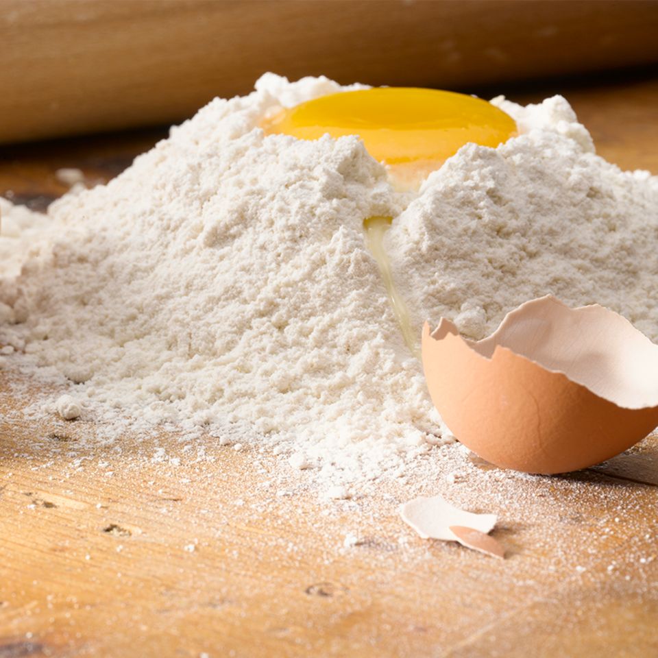 Eier, Mehl und ein Nudelholz auf einem Tisch