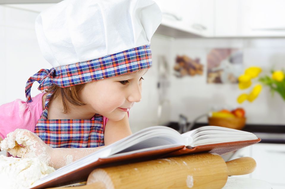 Kind mit Kochmütze und Kochbuch Kind mit Kochmütze und Kochbuch