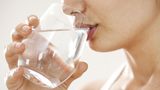 Frau trinkt aus Wasserglas