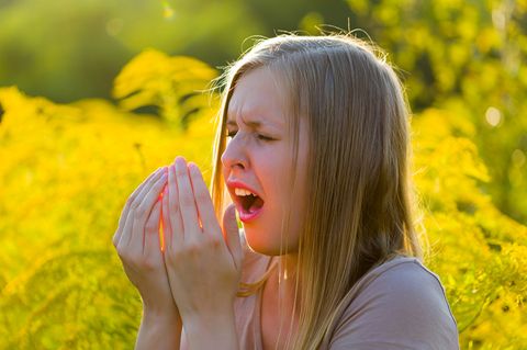 Junge Frau niest wegen Heuschnupfen
