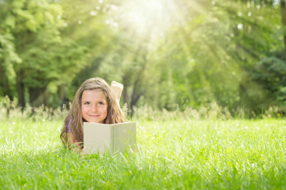 Mädchen liest auf der Wiese