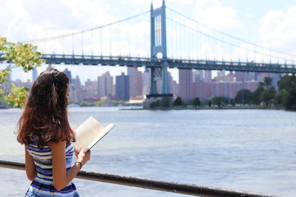 Frau liest Buch vor Brooklyn Bridge
