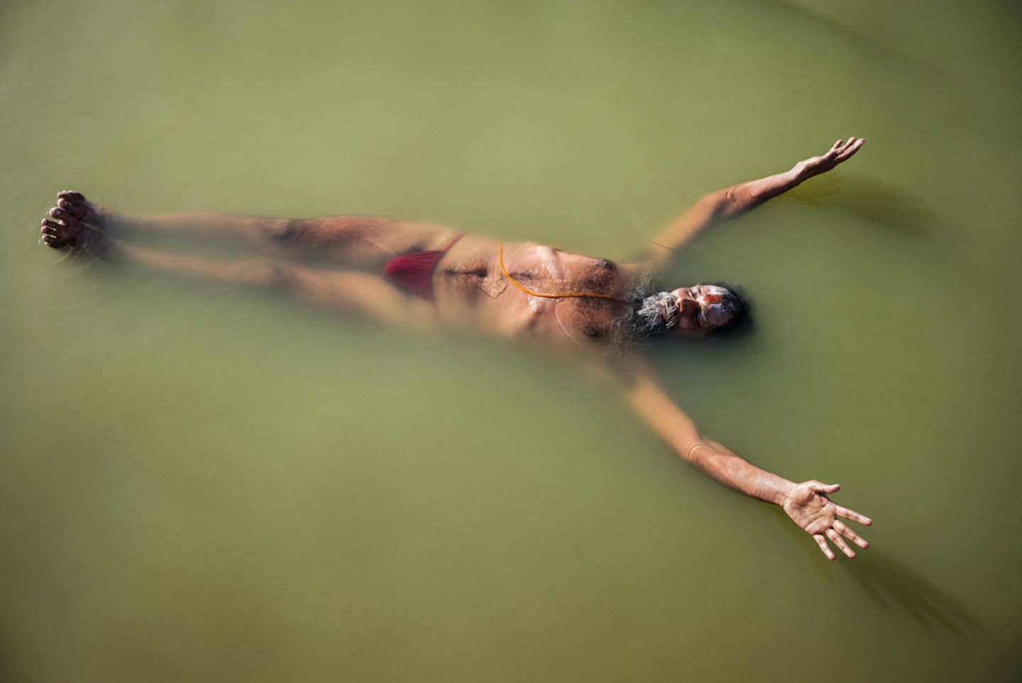 Ein Sadhu, ein heiliger Mann, schwebt im Wasser des Shipra und führt dabei  Plavini Pranayama aus, eine Atemübung