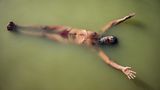 Ein Sadhu, ein heiliger Mann, schwebt im Wasser des Shipra und führt dabei  Plavini Pranayama aus, eine Atemübung