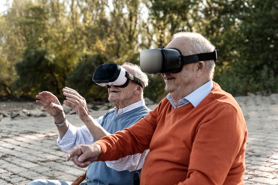 Zwei alte Freunde sitzen am Flussufer mit VR-Brille
