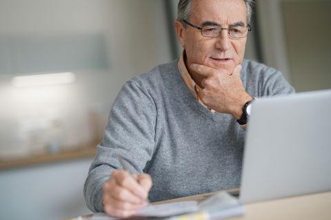 Älterer Mann sitzt am Laptop