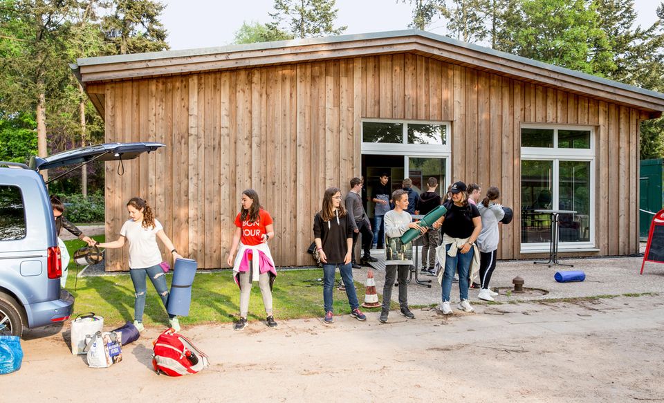 Die Schülerinnen und Schüler laden Isomatten und Schlafsäcke aus dem Elternauto aus. Die Schülerinnen und Schüler laden Isomatten und Schlafsäcke aus dem Elternauto aus.