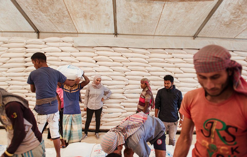Bangladesch: Aziza Mohamed Ali Bourgut überwacht die Verladung von Reissäcken, Nachschub für Hunderttausende Rohingya- Flüchtlinge. Die leitende Logistikerin versucht das Ziel des Welternährungs­programms (WFP) rigoros umzusetzen: »null Hunger«
