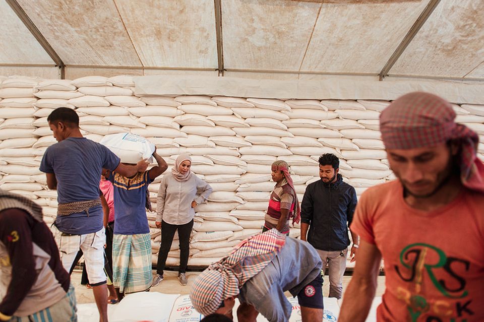 Bangladesch: Aziza Mohamed Ali Bourgut überwacht die Verladung von Reissäcken, Nachschub für Hunderttausende Rohingya- Flüchtlinge. Die leitende Logistikerin versucht das Ziel des Welternährungs­programms (WFP) rigoros umzusetzen: »null Hunger«