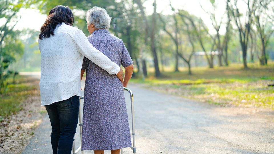 Eine junge Frau hilft einer alten Frau beim Gang über die Straße