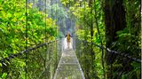 Frau schreitet über eine Hängebrücke im Urwald Costa Ricas