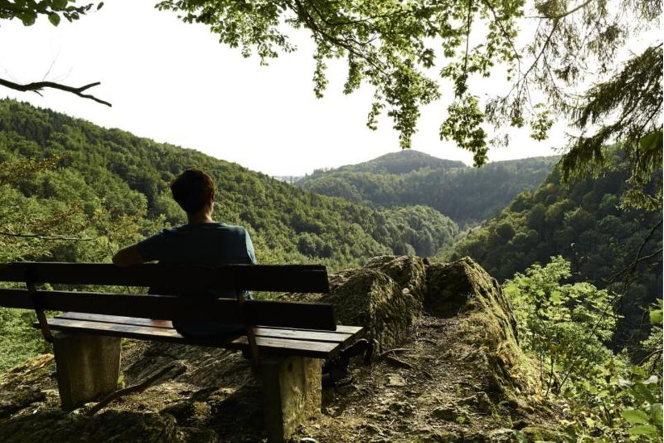 Wanderer auf einer Bank genießt die Aussicht über das Steinachtal Wanderer auf einer Bank genießt die Aussicht über das Steinachtal