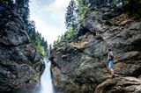 Mann betrachtet von einem Felsen aus den Buchenegger Wasserfall