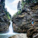 Mann betrachtet von einem Felsen aus den Buchenegger Wasserfall