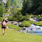 Wandernde Frau am Fluss in den Alpen
