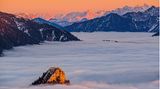 Dieses Bild entstand an einem klaren Novemberabend auf der Hochplatte. Gerade eben noch sticht die Spitze des Leonhardsteins aus dem Hochnebel hervor, dahinter glühen die zackigen Gipfel des Wilden Kaisers und der Loferer Steinberge.