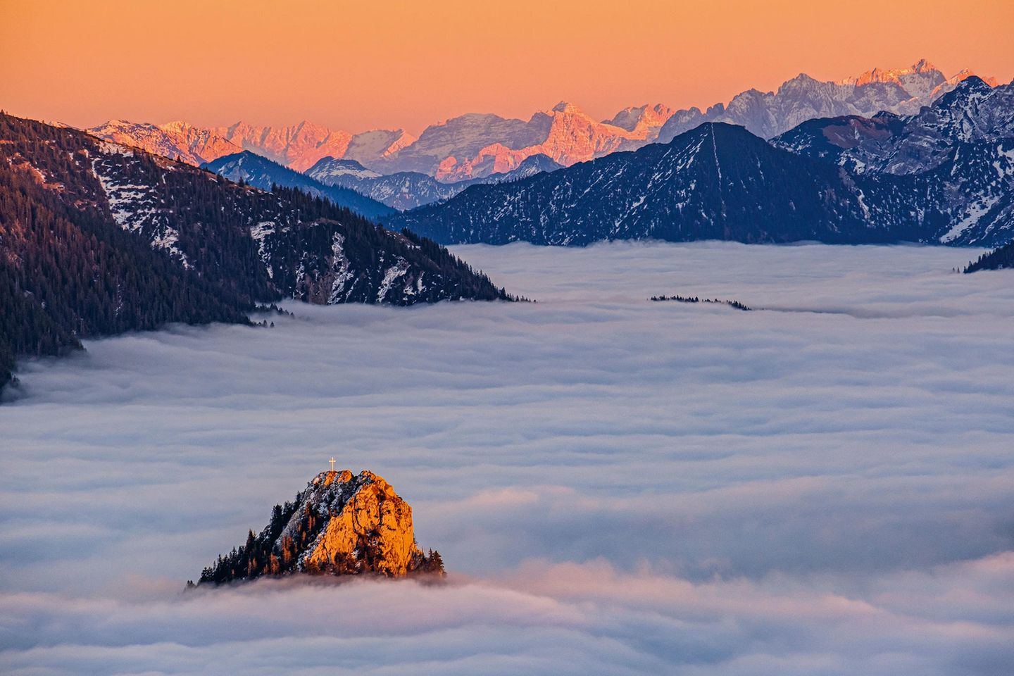Dieses Bild entstand an einem klaren Novemberabend auf der Hochplatte. Gerade eben noch sticht die Spitze des Leonhardsteins aus dem Hochnebel hervor, dahinter glühen die zackigen Gipfel des Wilden Kaisers und der Loferer Steinberge.
