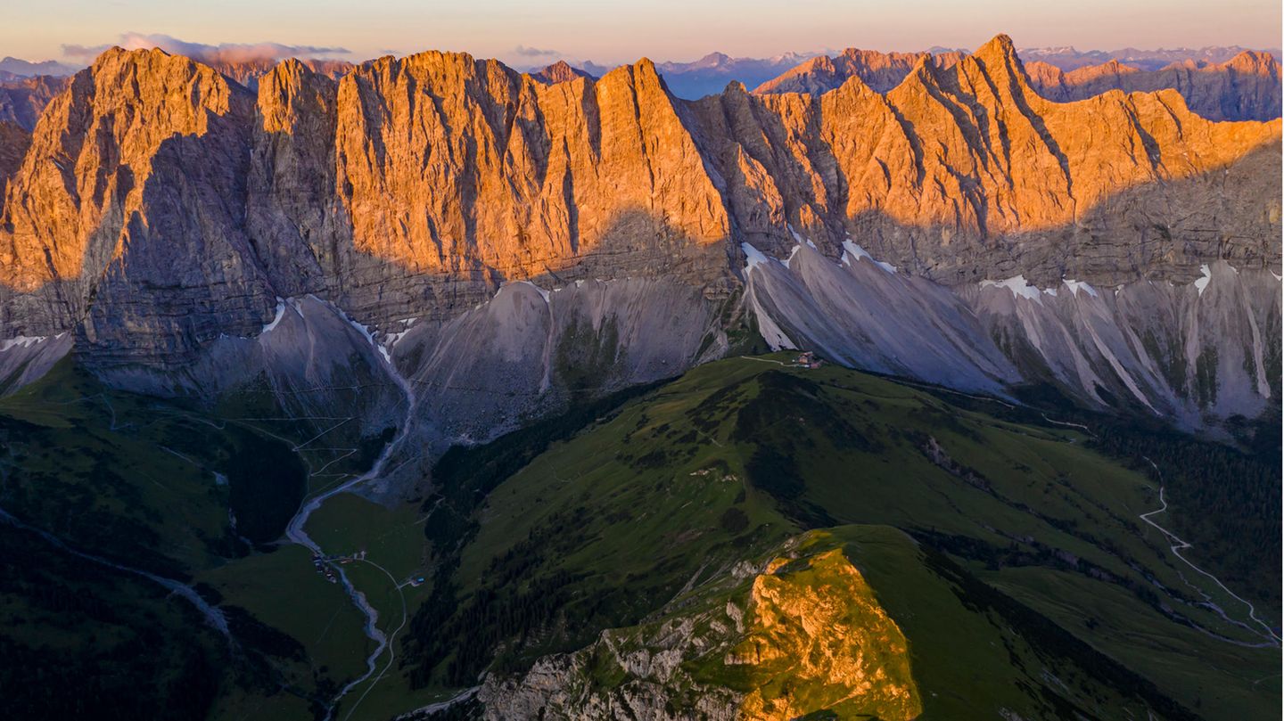 Die Szenerie erinnert an Patagonien. Markante Felsklippen strahlen golden im Abendlicht, tief unten liegen die eingeschnittenen Täler bereits im Dunkeln