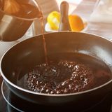 Rotwein, der beim Kochen in eine Pfanne gegossen wird