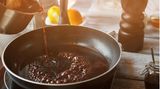 Rotwein, der beim Kochen in eine Pfanne gegossen wird