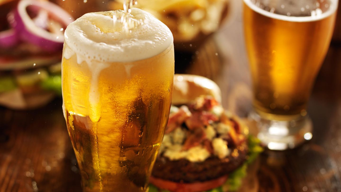 "Bier macht dick" Volles Bierglas auf Esstisch mit Fast Food